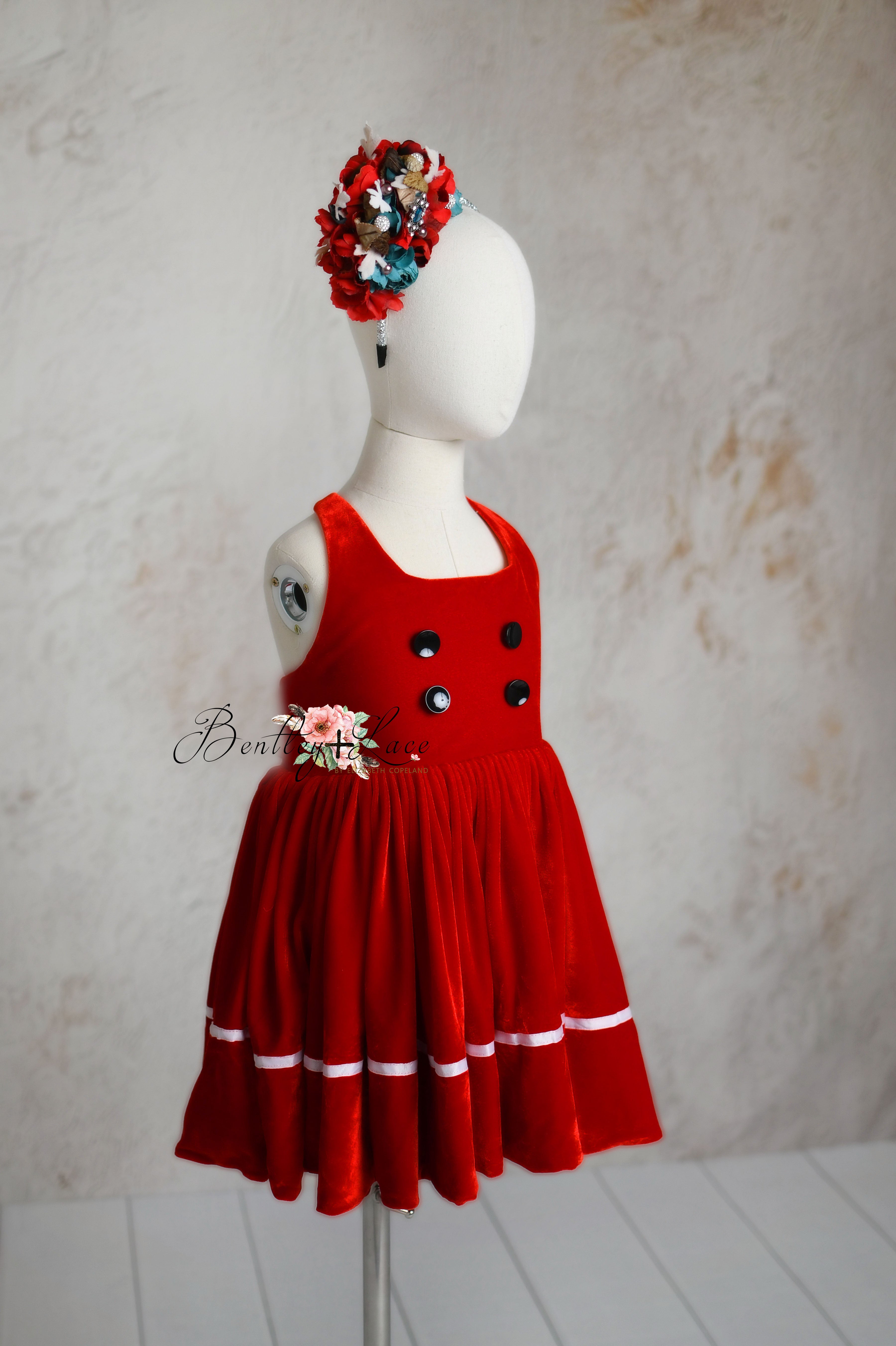 Complete holiday outfit for kids featuring a red velvet apron dress and matching floral headband.