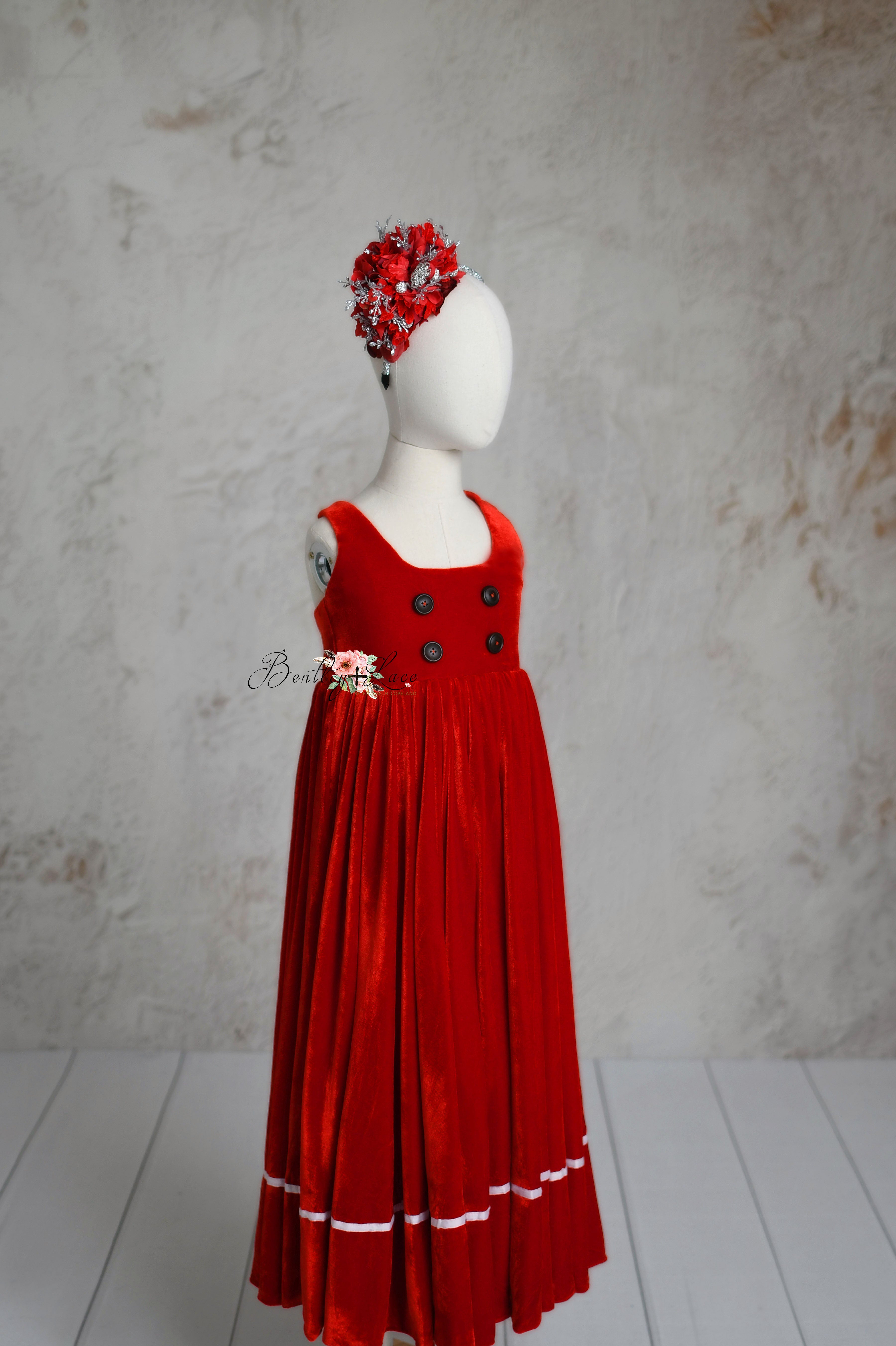 Red velvet Christmas dress for children, complete with a matching floral headband and elegant pleated skirt.