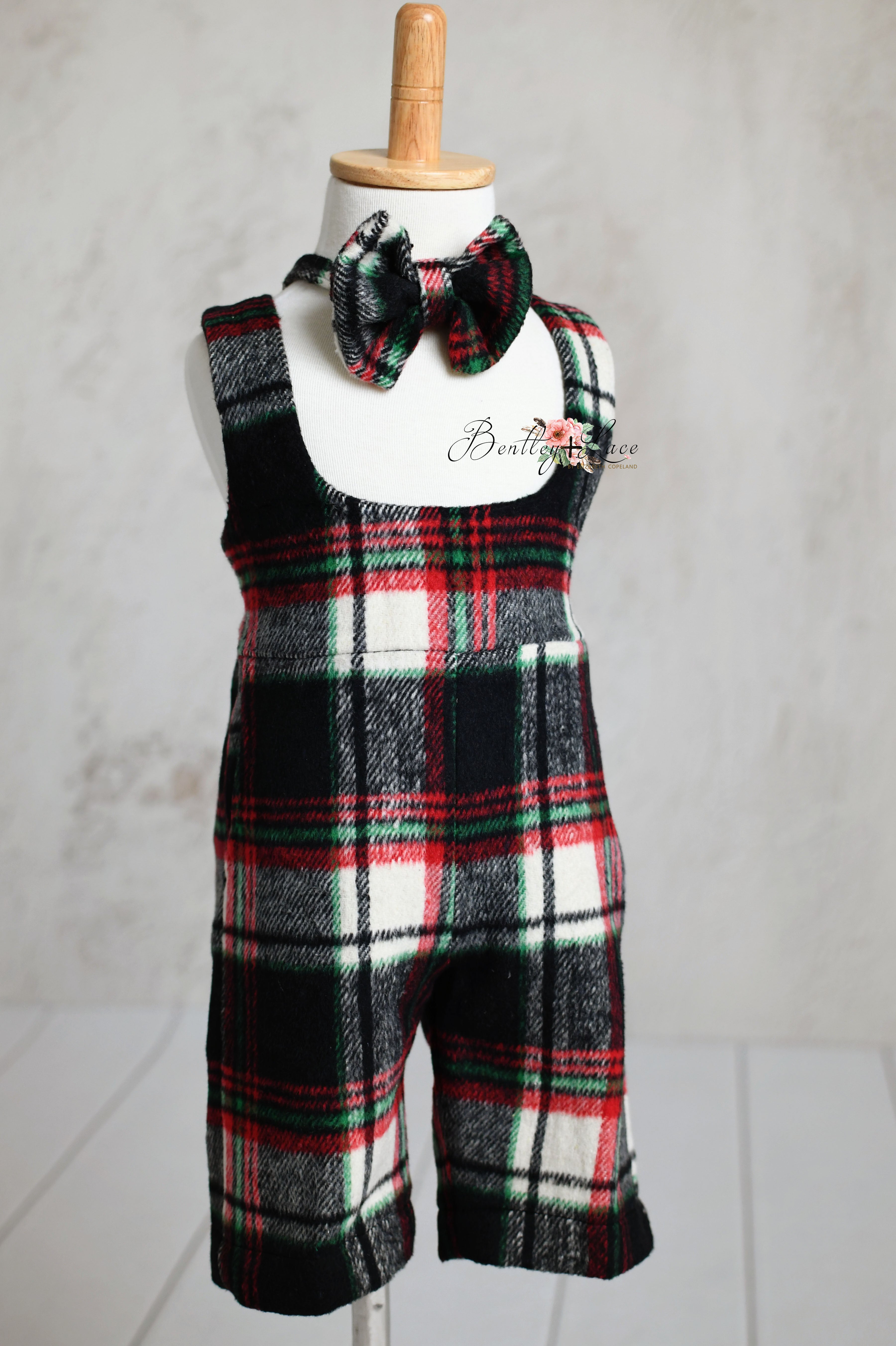 Classic plaid toddler outfits in red, black, and white, featuring bow ties, on display.