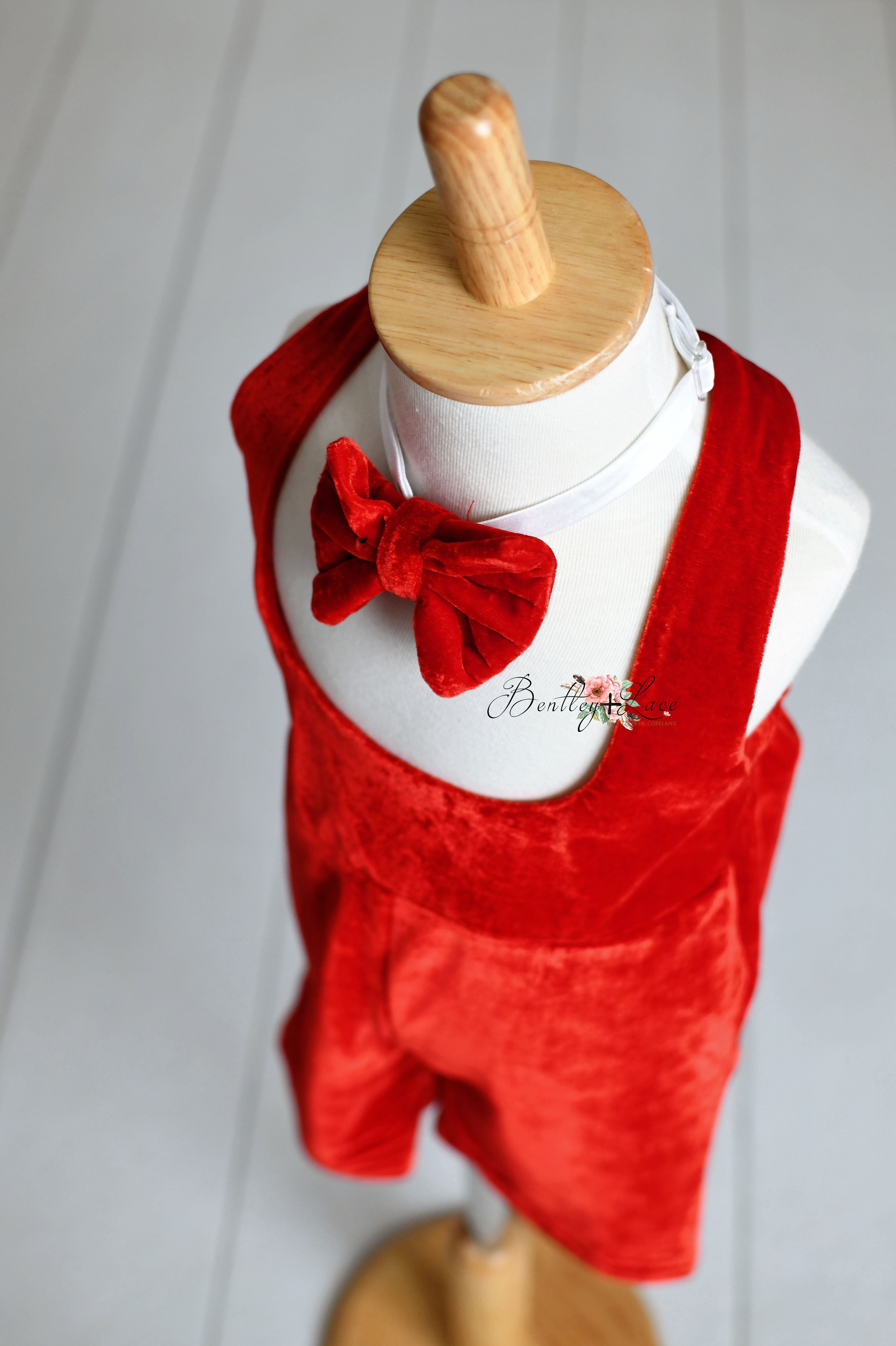 Two red velvet toddler outfits with bow ties, styled on mannequins against a neutral background