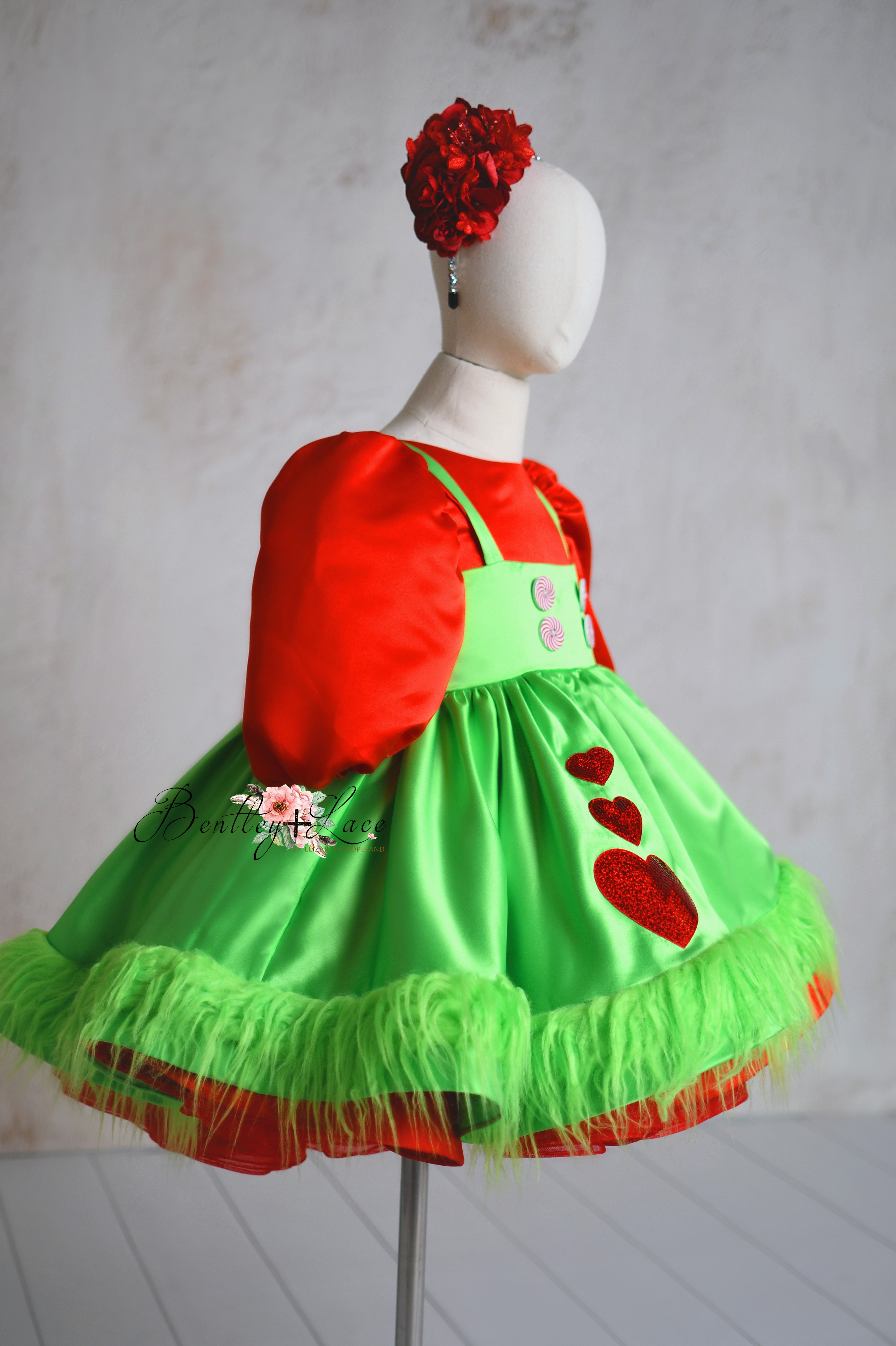 Red and green Mischief-Maker Set with a detachable apron, peppermint buttons, red hearts, and fluffy green trim.
