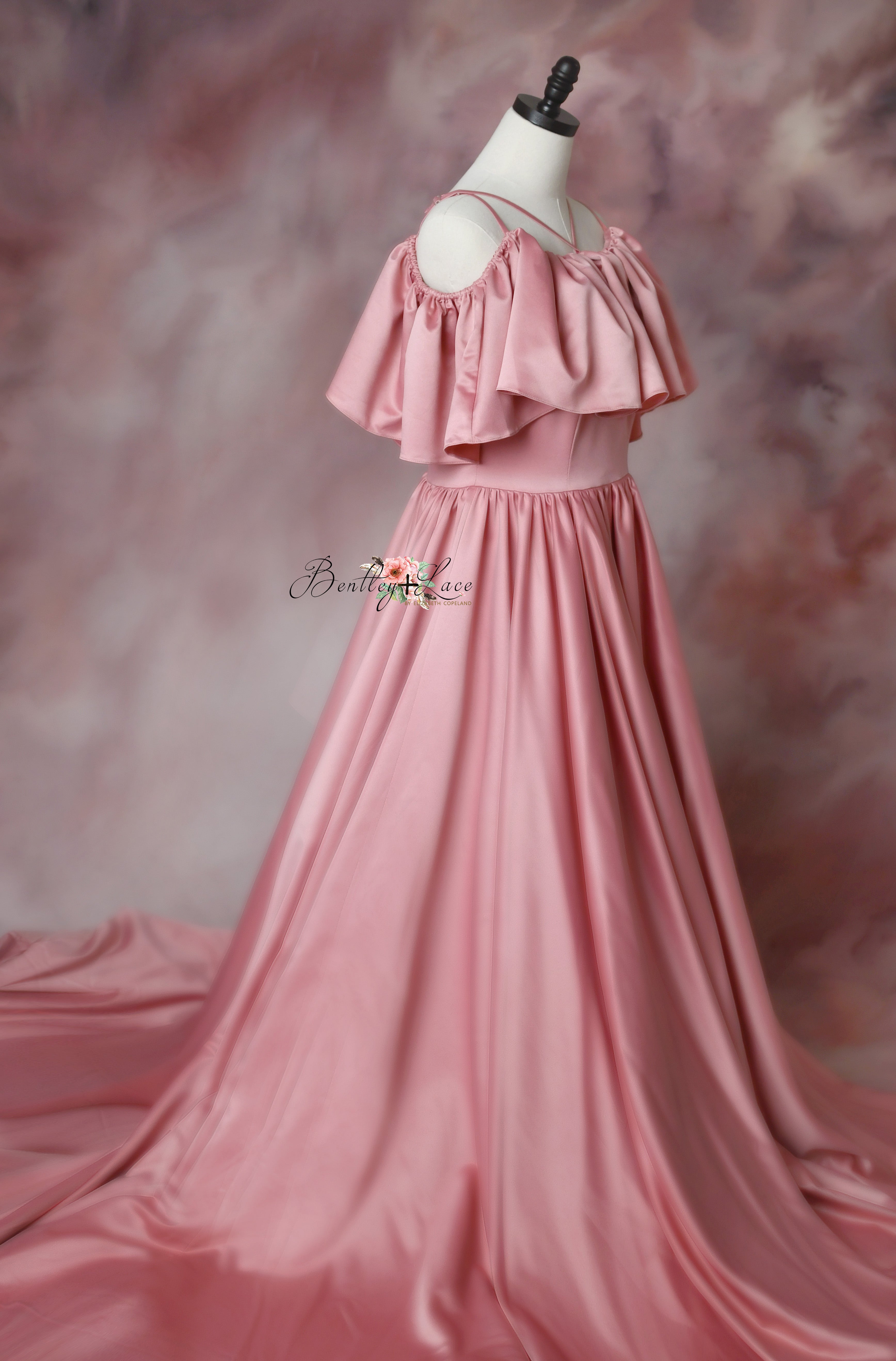 Beautiful pink satin dress with shoulder cutouts and a full-length train, styled for photography.