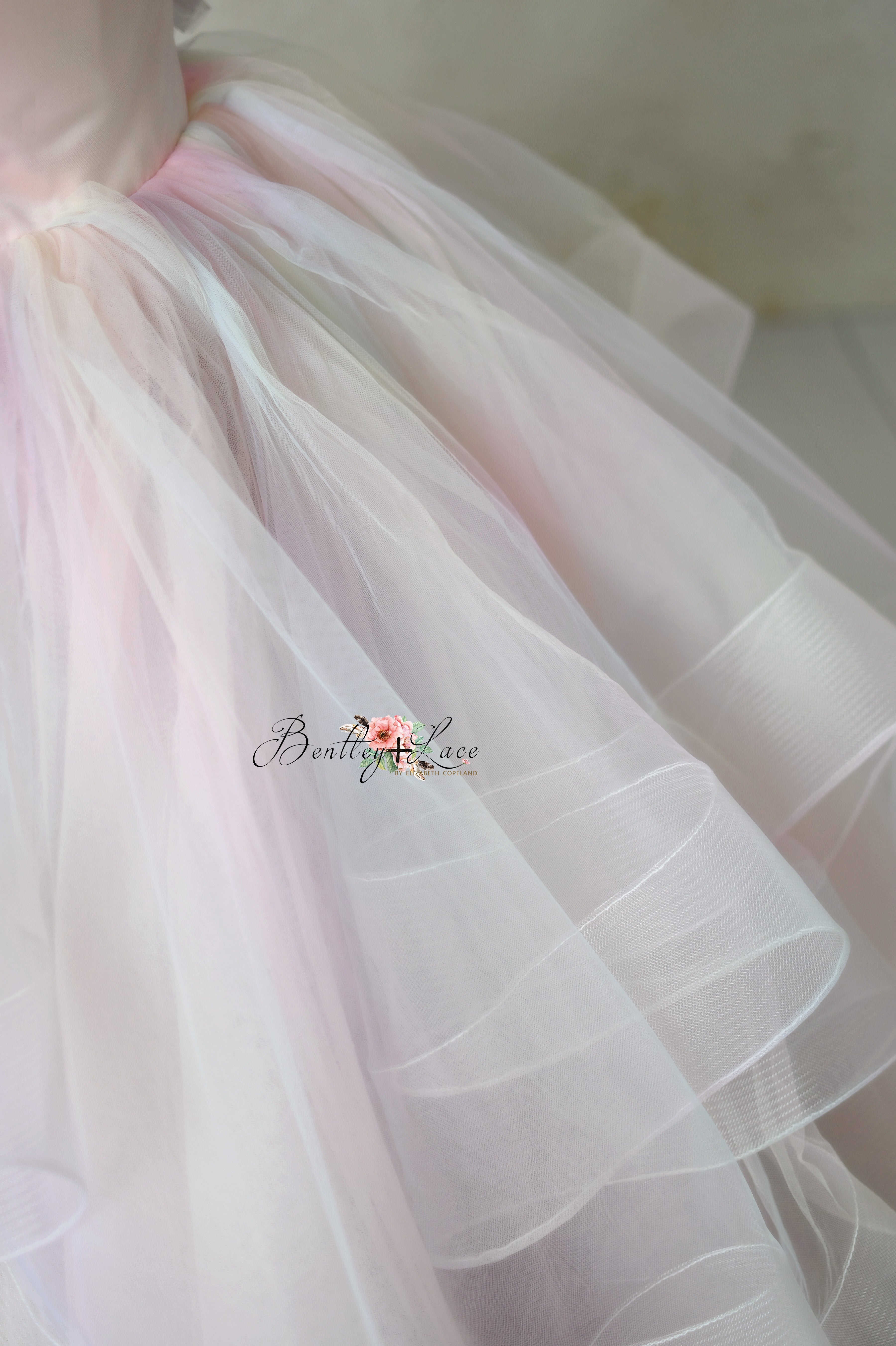 Soft pastel-colored Chasing Rainbows gown with flowing skirt and detachable tulle sleeves for a graceful look.
