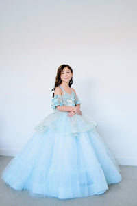 "Soft champagne and blue shades intertwining in the Trésor Caché gown, creating a dreamy and ethereal look."

