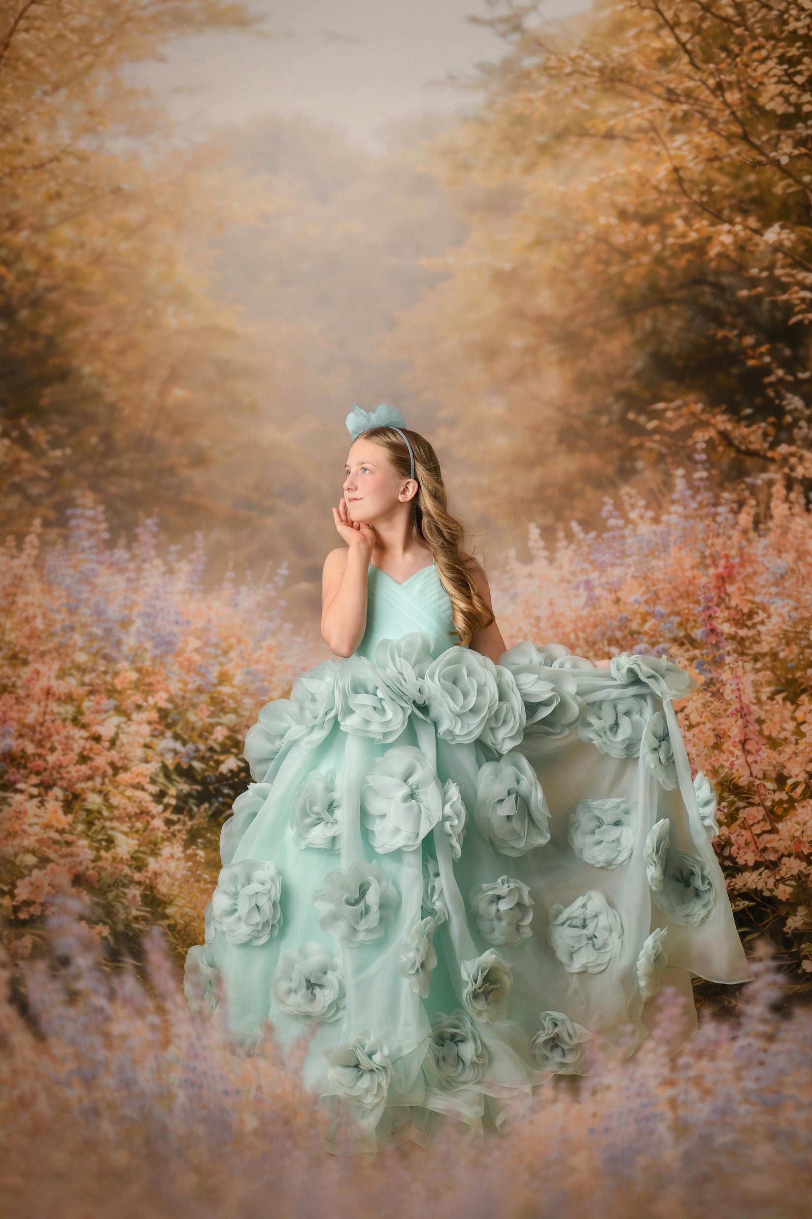Woman in a light blue floral dress standing in a forest with autumn foliage.
