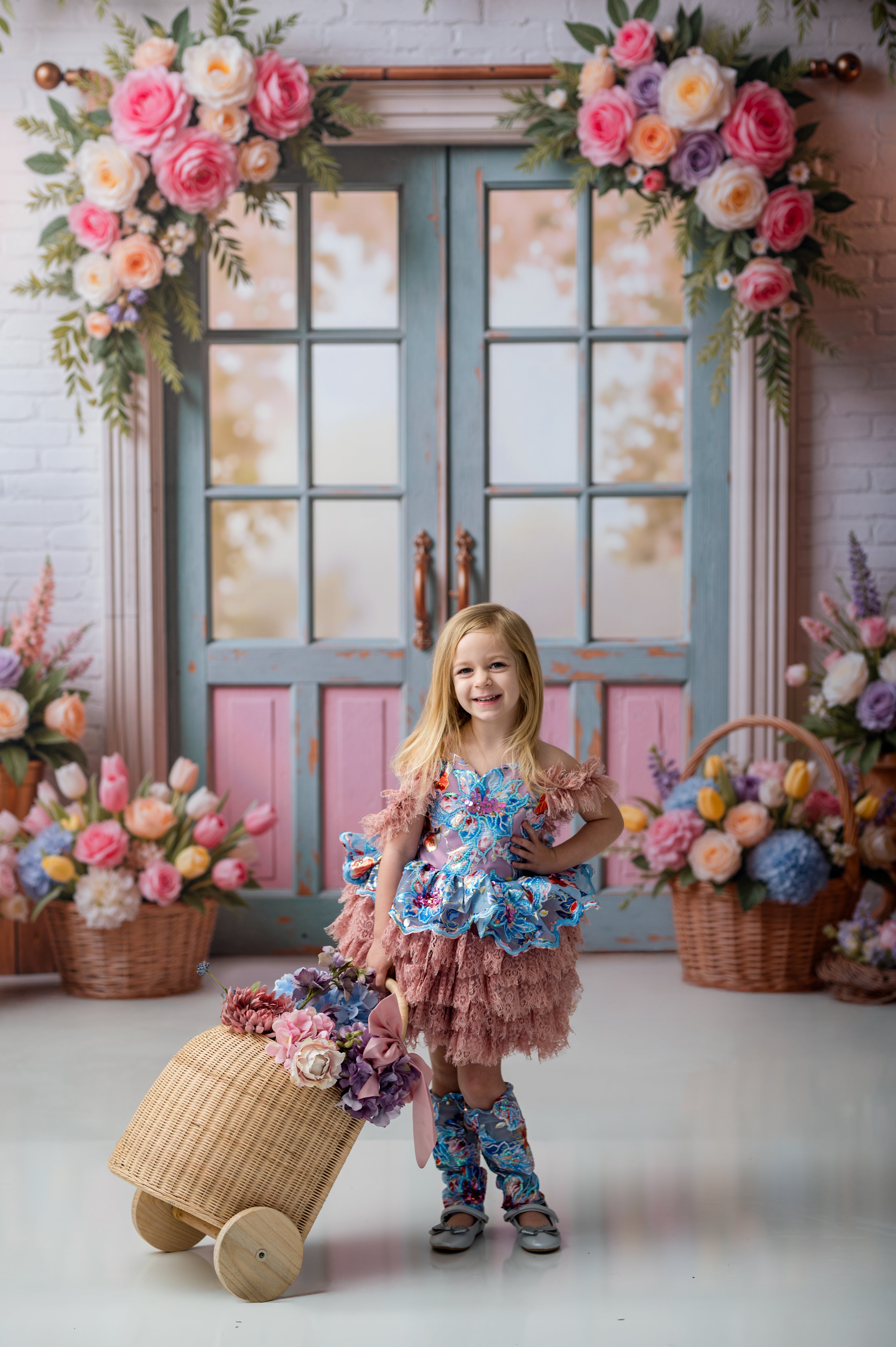 Young girl in a floral dress standing in a decorated room with flowers and a suitcase.