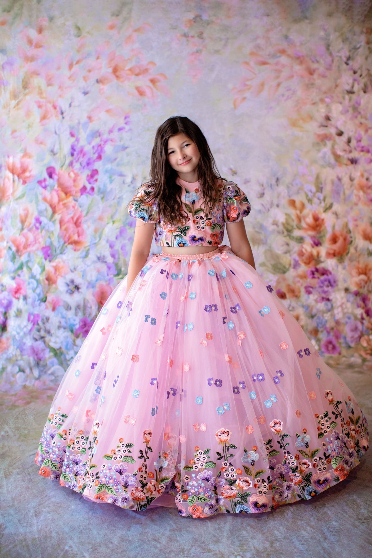 Woman in a floral dress standing against a floral wall.