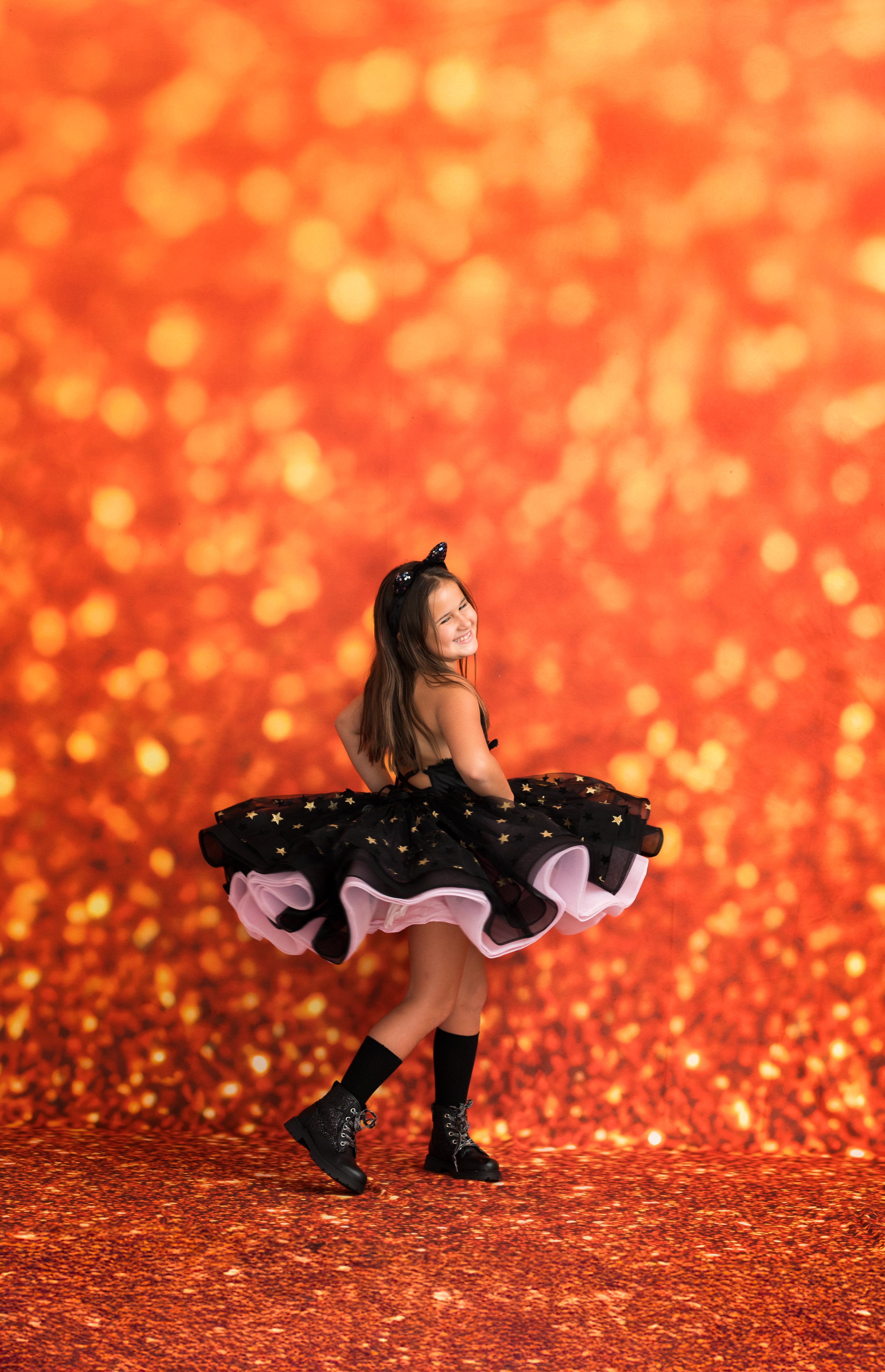 Child in a black and white polka dot dress with a red glittery background