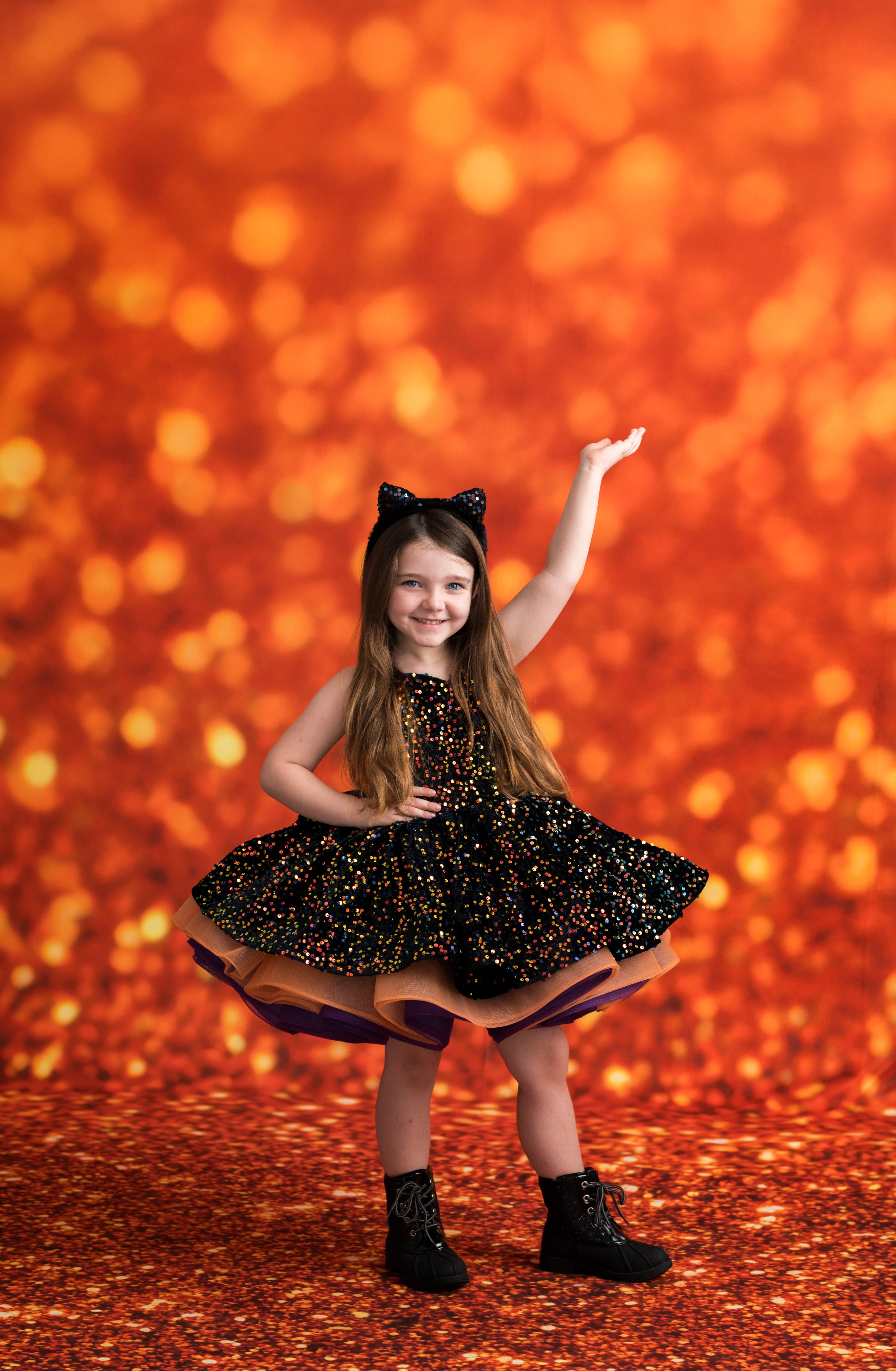 Young girl in a black dress with cat ears against an orange glittery background