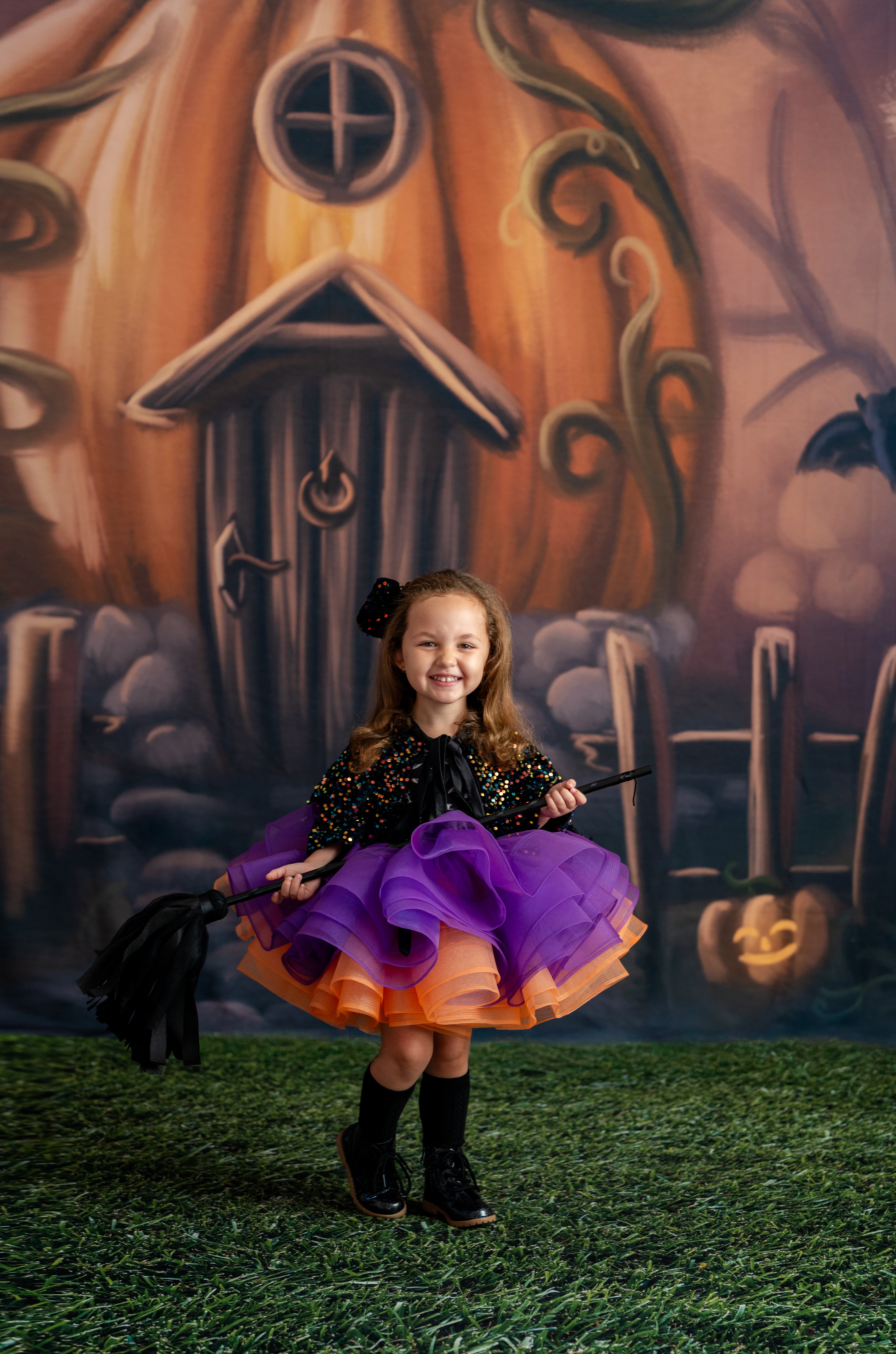 Child in Halloween costume with pumpkin house backdrop