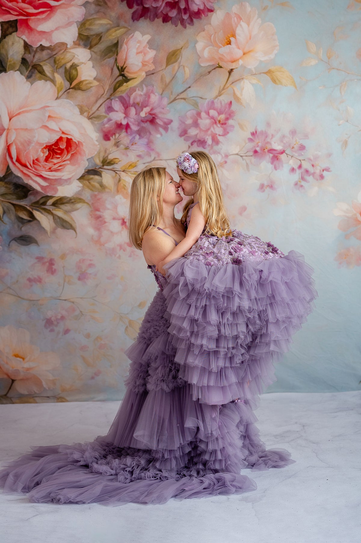 Mother twirling with daughter in matching lavender tulle gowns with floral accents.


