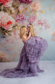 Mother twirling with daughter in matching lavender tulle gowns with floral accents.

