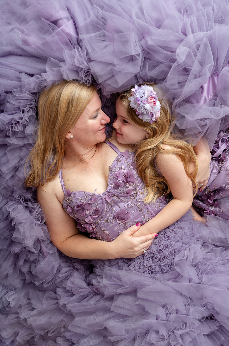 Mommy and me portrait in coordinating Violet Grace lavender tulle gowns surrounded by flowers.

