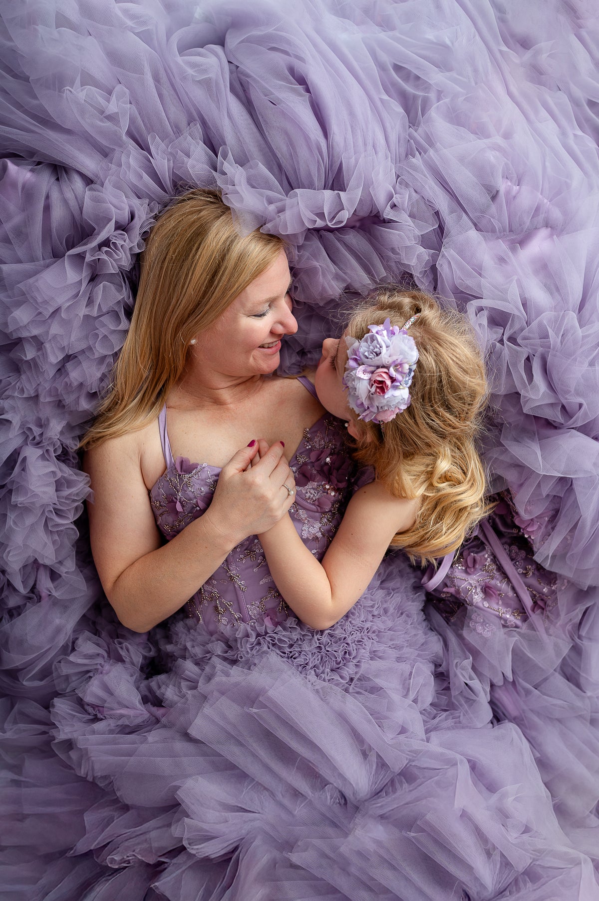 Mom and little girl in coordinating Violet Grace gowns with pastel floral accents and soft sunlight.

