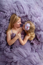 Mom and little girl in coordinating Violet Grace gowns with pastel floral accents and soft sunlight.

