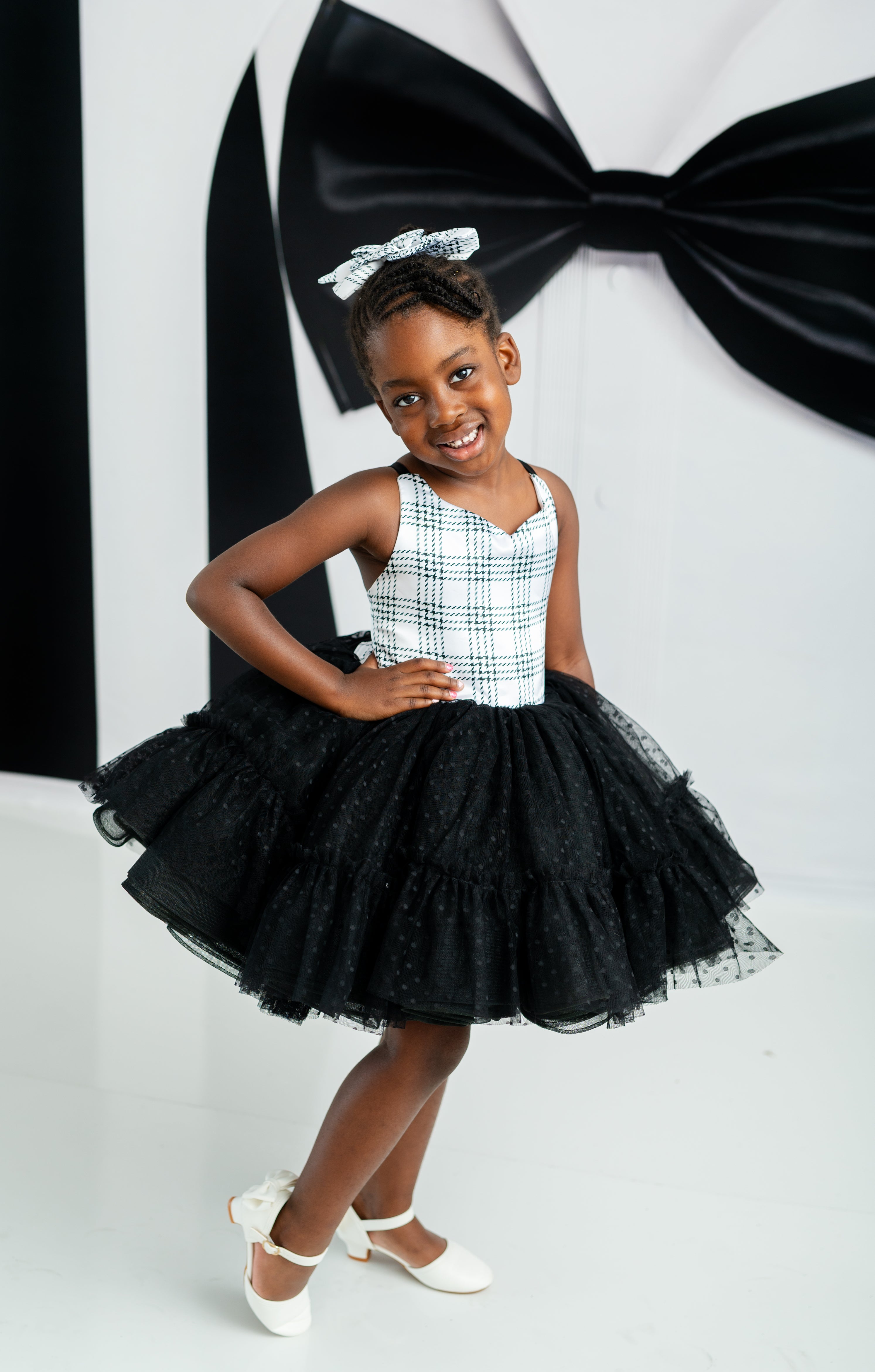 Young girl in a black and white dress with a large black bow in the background