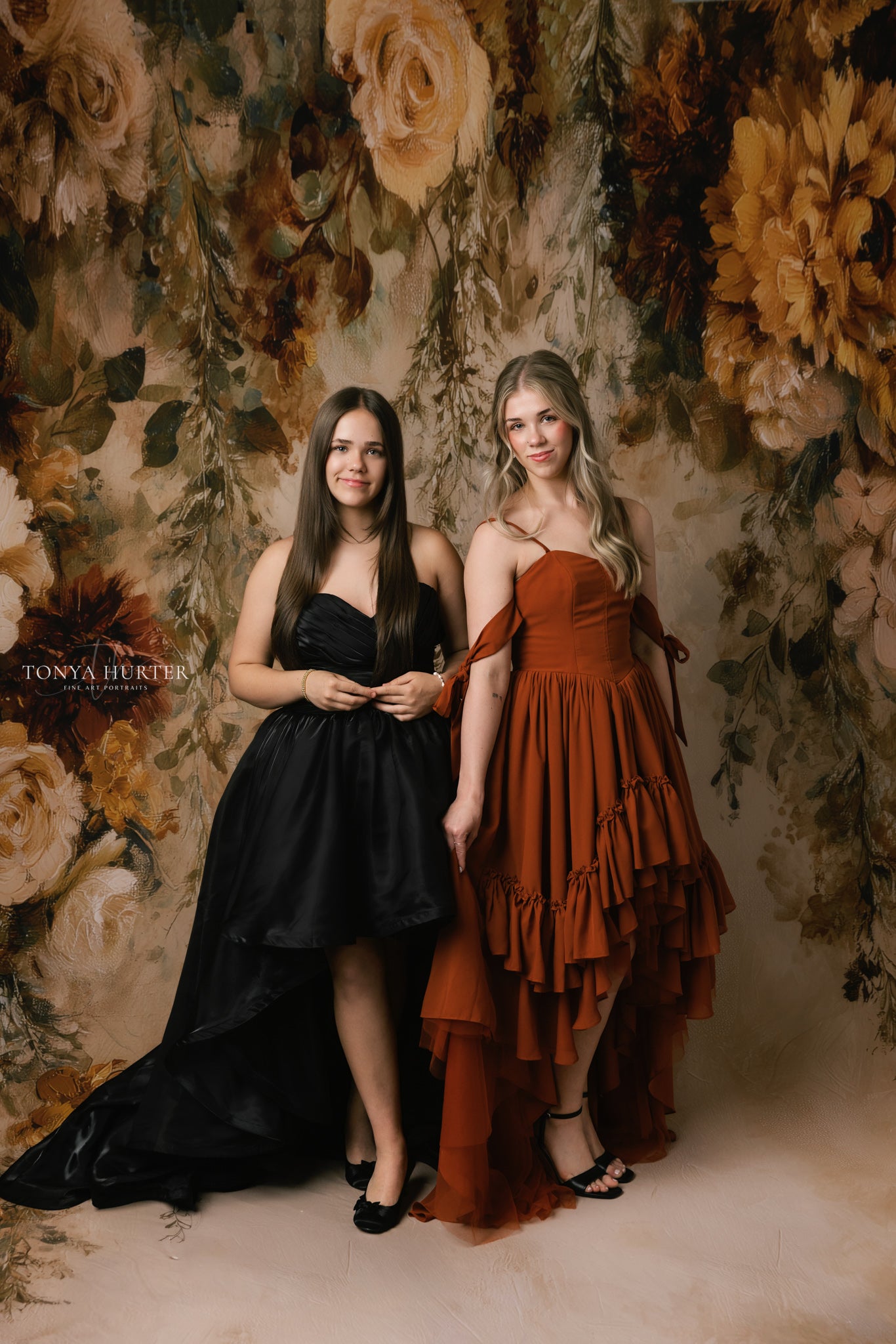 Two women in formal dresses standing against a floral backdrop with 'Tonia Herter' branding.