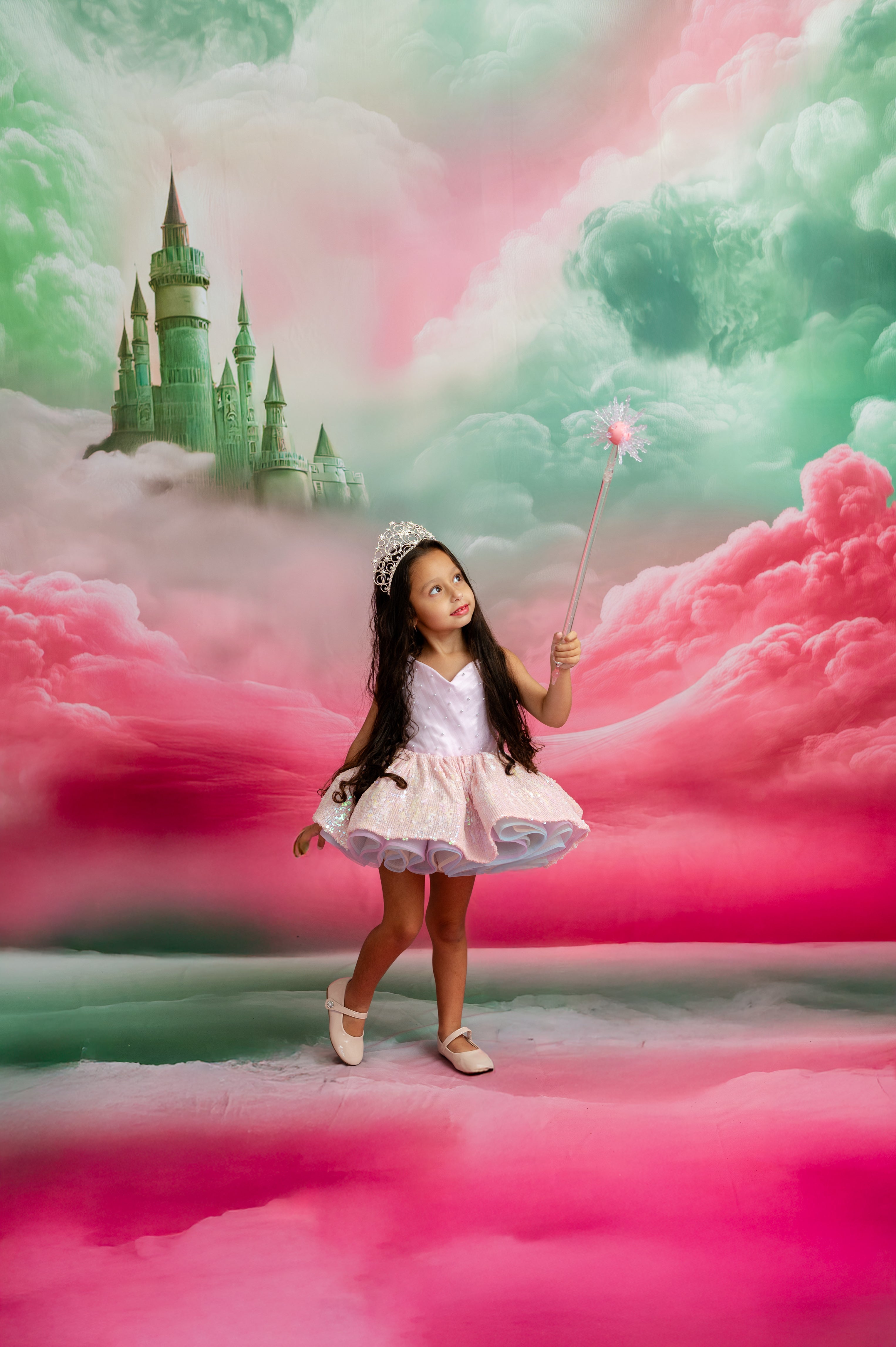 Young girl in a fairy tale setting with a castle and pink clouds