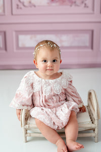 Baby girl wearing The Rosalie Romper in blush velvet and lace

