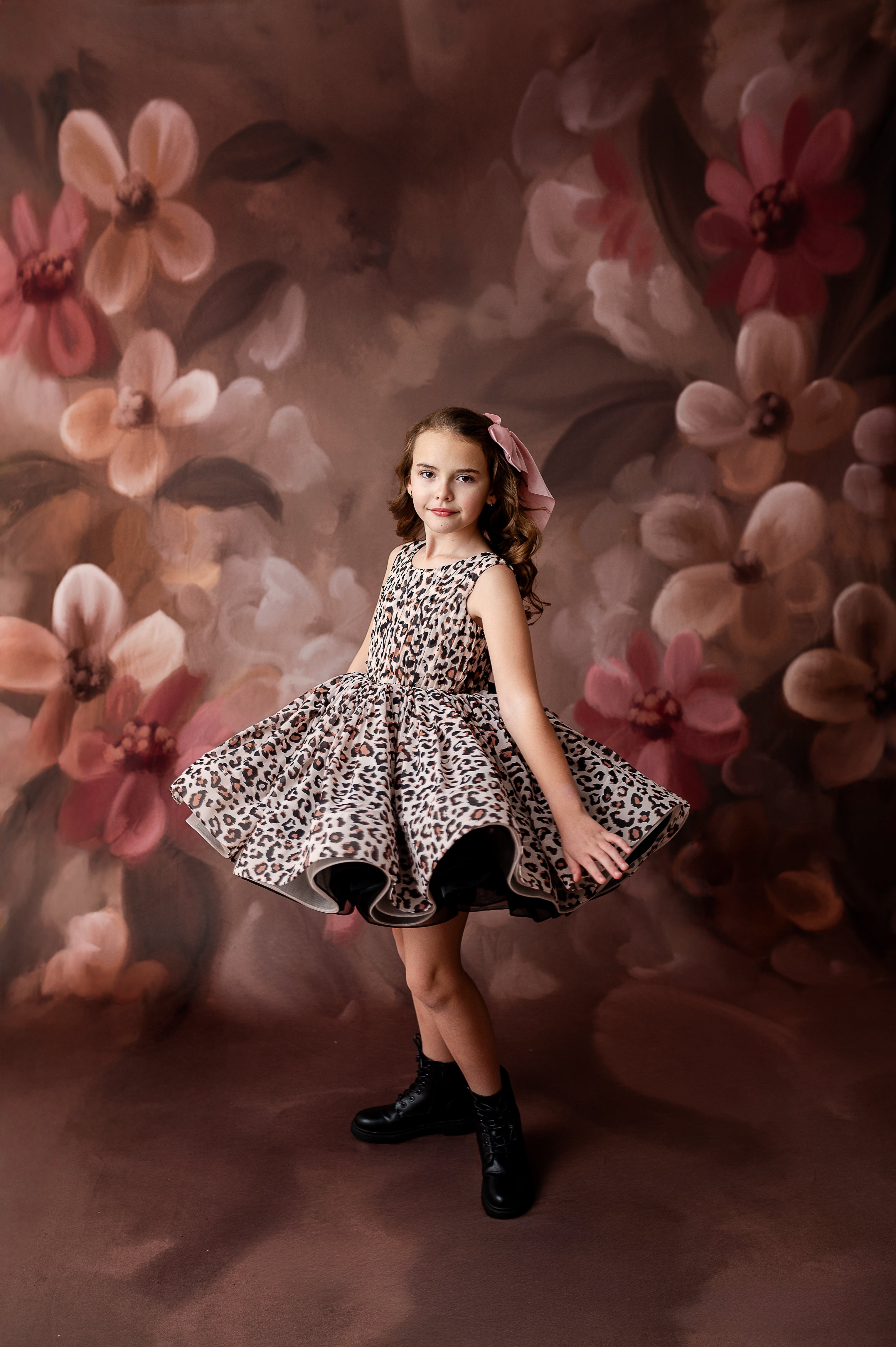 "Modern and timeless: a little girl in a leopard dress poses gracefully for a birthday or event-themed photoshoot."
