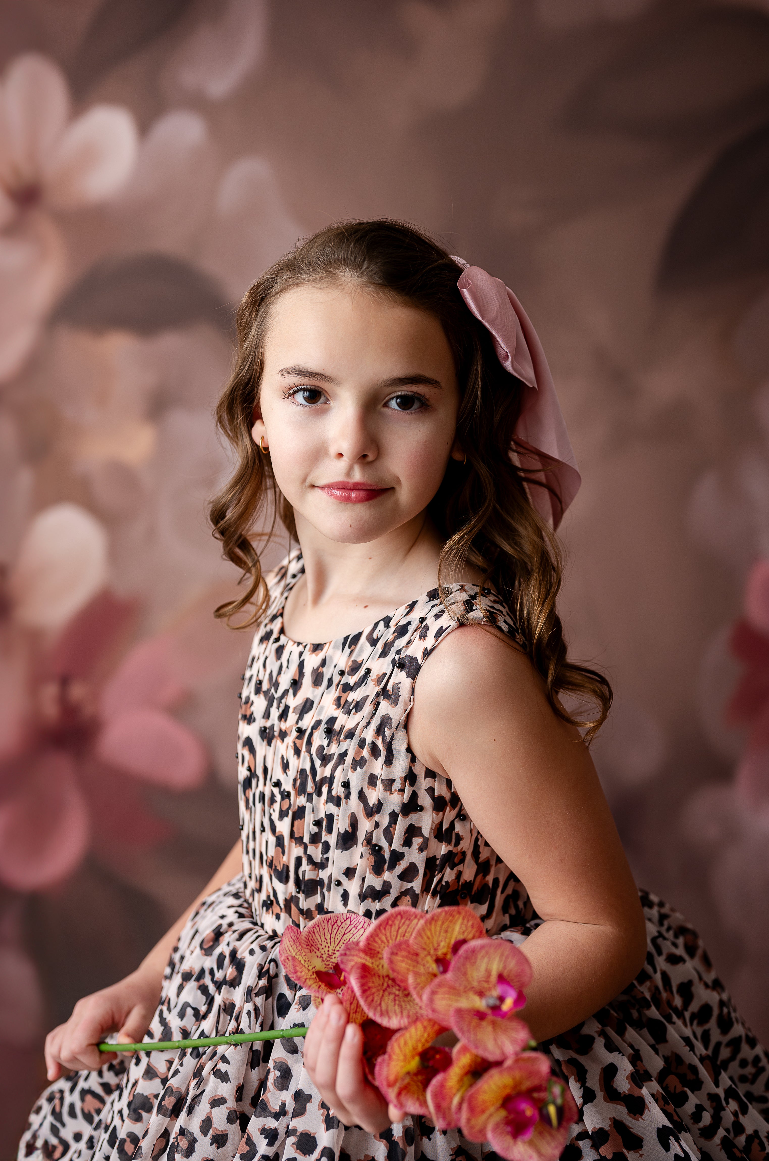 "Special occasion photography featuring a charming girl in a ruffled leopard print dress holding an open frame."
