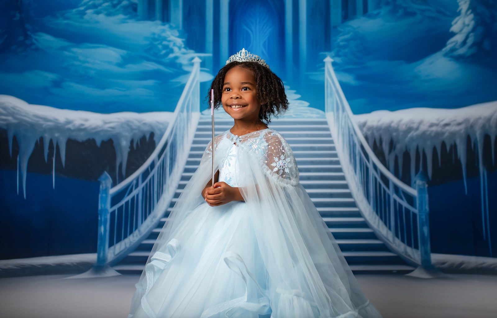 Elegant, Elsa-inspired gown in a frosty blue with sparkling accents, worn by a model in a snowy photoshoot setting. Perfect for winter and holiday photography.