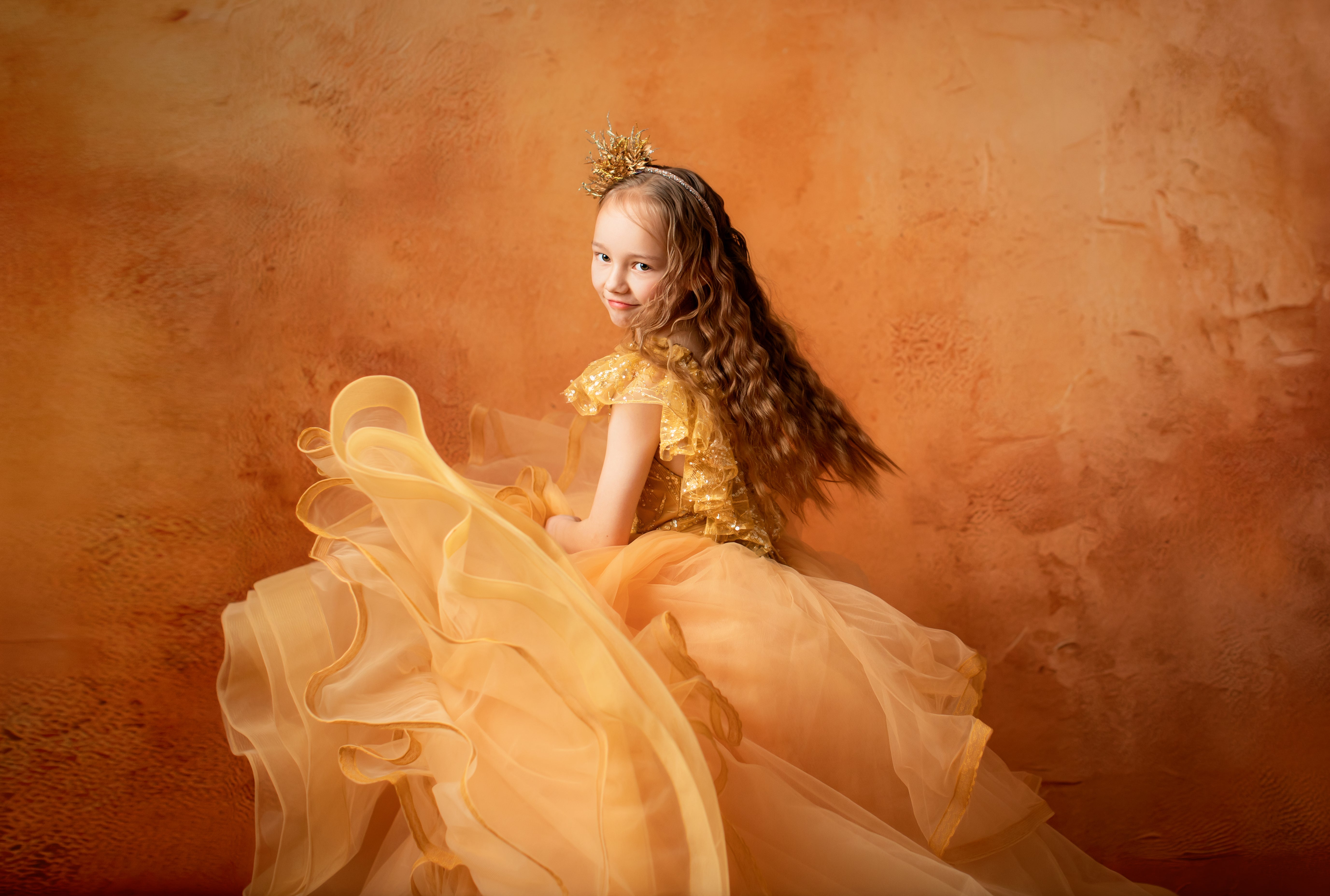 Young girl in a yellow dress against an orange textured wall