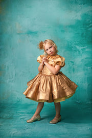 "Girl in a luxurious gold gown with dramatic puff sleeves, posing gracefully."
