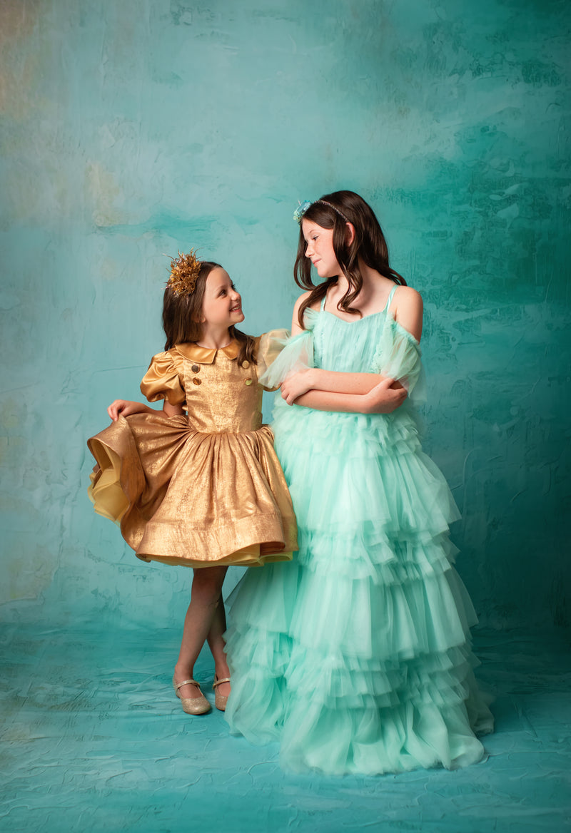 "Mint green tiered gown with delicate off-shoulder straps and floral headpiece."
