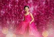 Young girl in a pink sequin dress against a pink glittery background