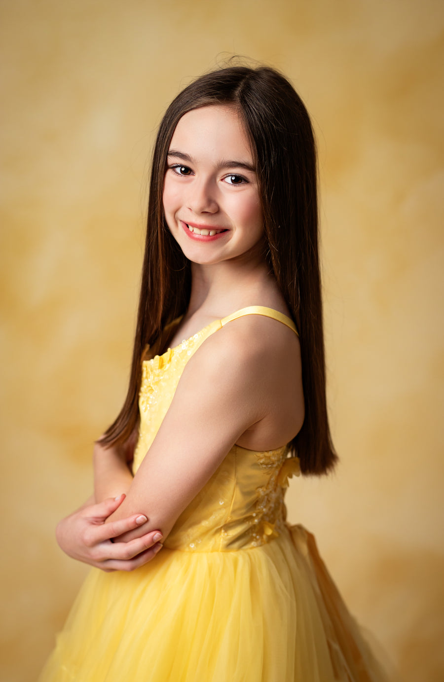 Golden hour goddess – A girl in a sunshine-yellow dress poses gracefully, the backdrop blending perfectly with her luminous gown.

