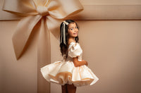 Young girl in a white dress standing next to a large gift box with a bow on a beige background