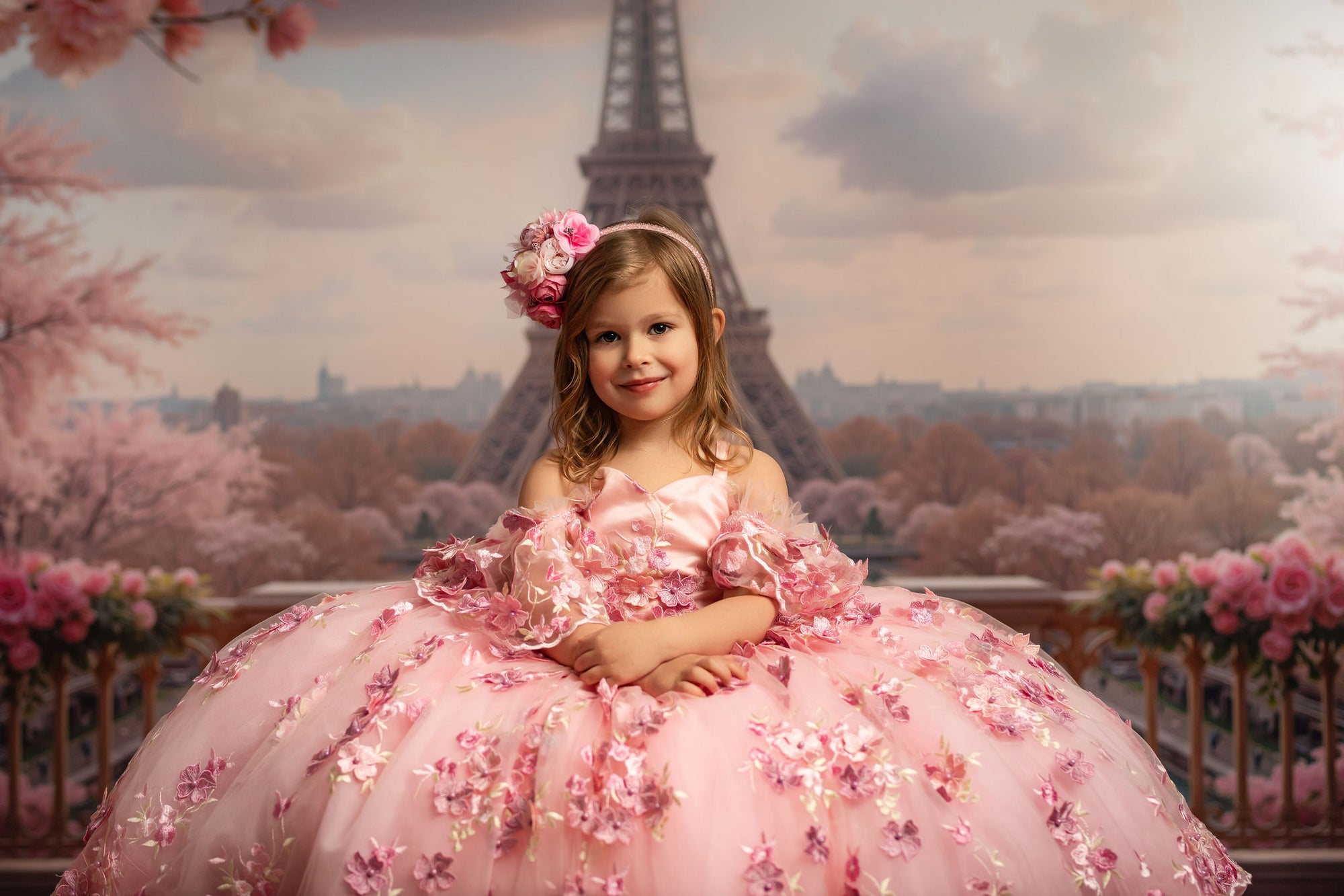 Young girl in a pink floral dress standing in front of the Eiffel Tower with cherry blossoms.