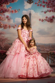 Two women in pink dresses standing in front of the Eiffel Tower with cherry blossom trees.