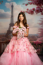 Woman in a pink floral dress holding flowers with the Eiffel Tower and cherry blossoms in the background