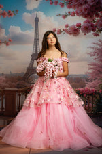 Woman in a pink dress holding flowers with the Eiffel Tower and cherry blossoms in the background