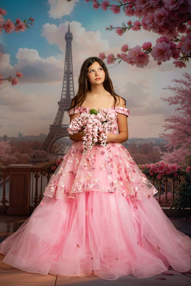Woman in a pink dress holding flowers with the Eiffel Tower and cherry blossoms in the background