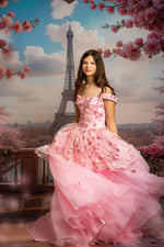 Woman in a pink dress standing in front of the Eiffel Tower with cherry blossoms.