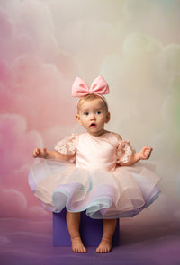 Baby in a pink dress with a large bow on a colorful background