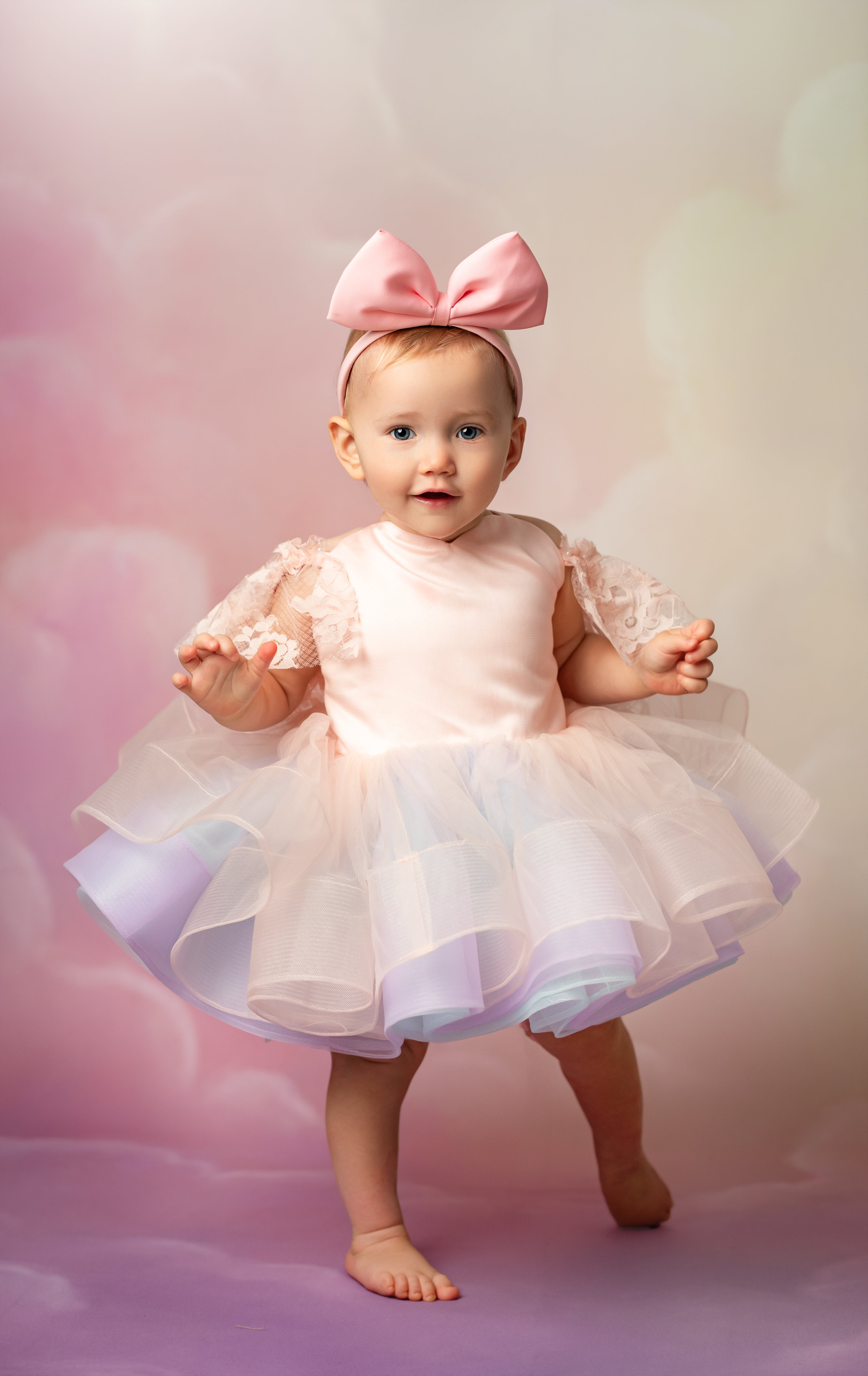 Baby in a pink dress with a large bow on a soft, blurred background