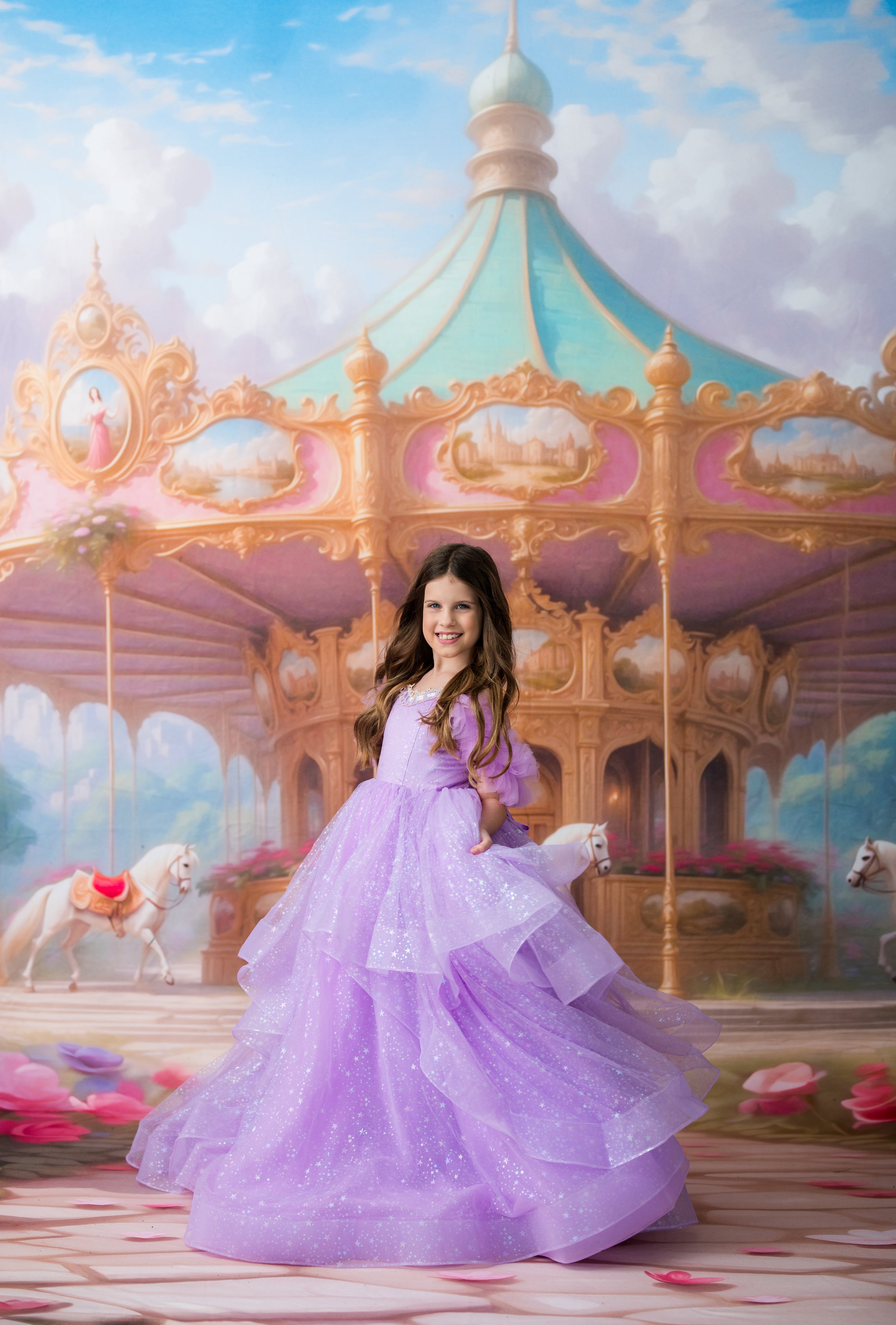 A young girl with long dark hair stands in front of a painted carousel scene, wearing a voluminous lavender-purple glittery ball gown. The background shows a pastel carousel with white horses under a blue sky.