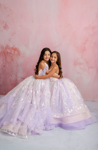 Two young girls in sparkling dresses posing against a pink textured background