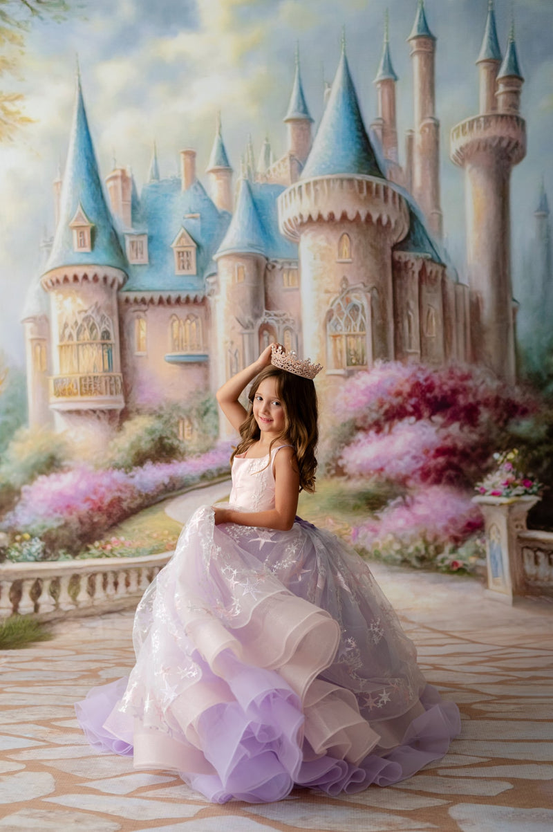 Young girl in a princess dress sitting in front of a fantasy castle with colorful architecture.