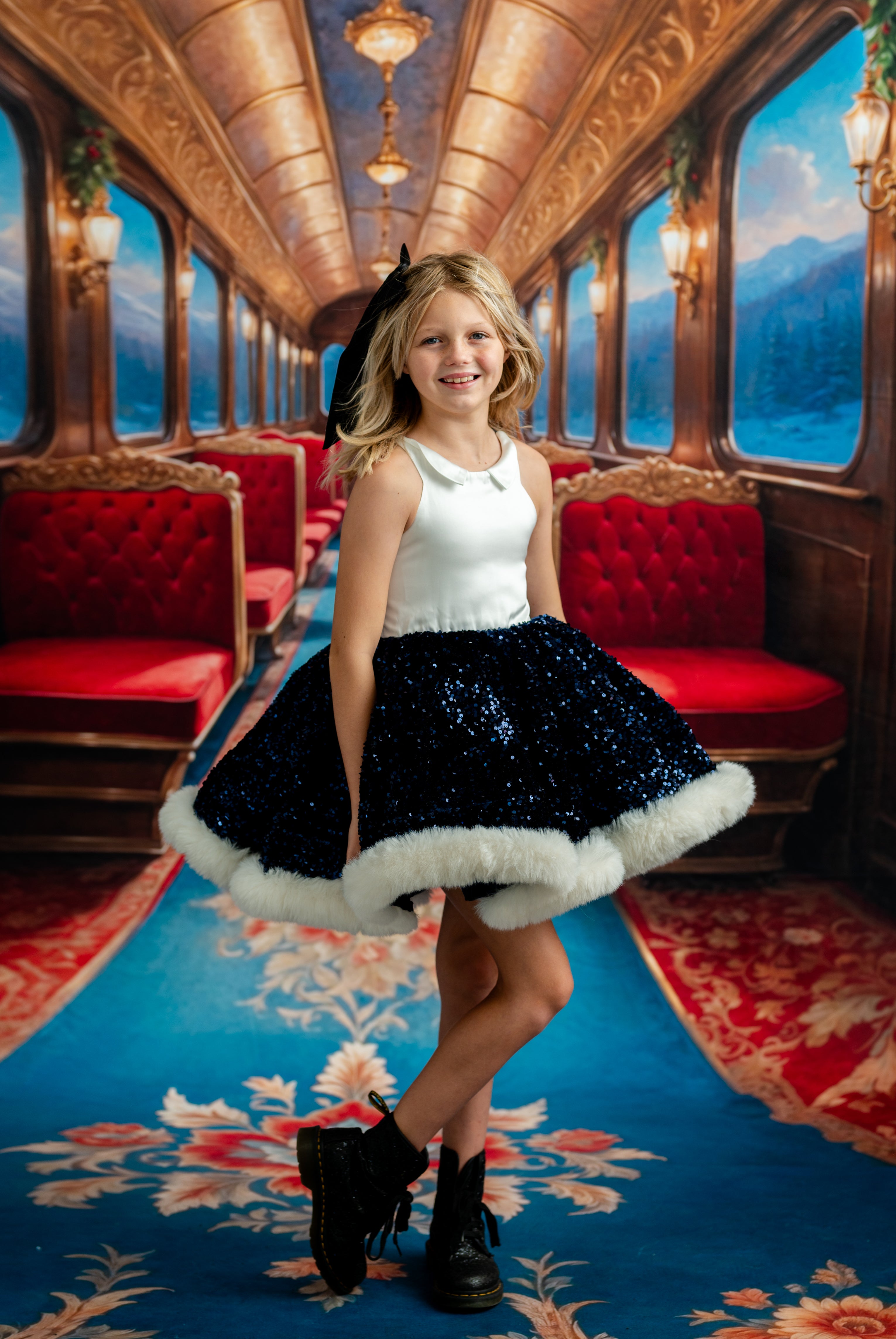 Young girl in a decorated train car with red seats and ornate ceiling.