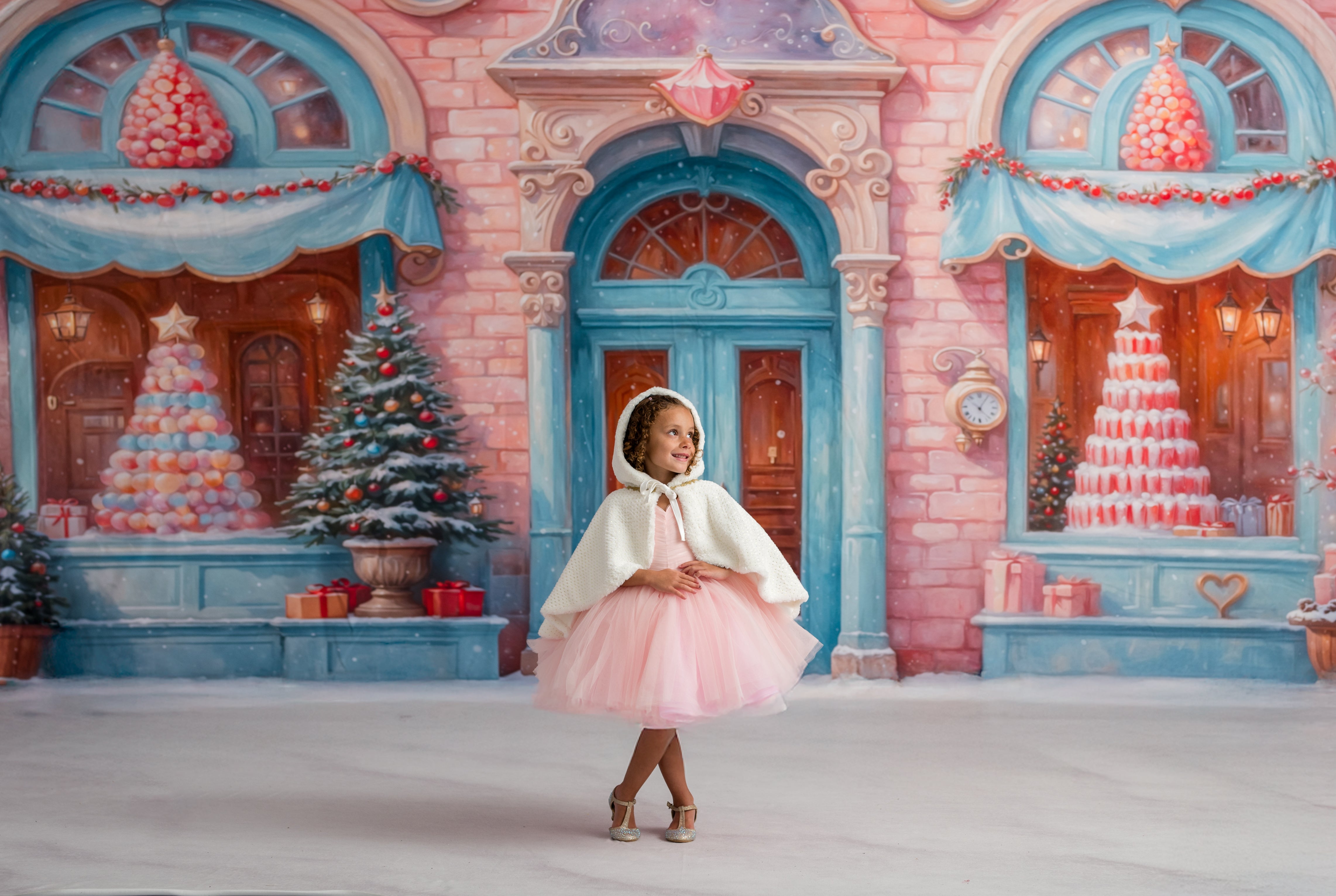Young girl in a pink dress standing in front of a festive, candy-themed house.