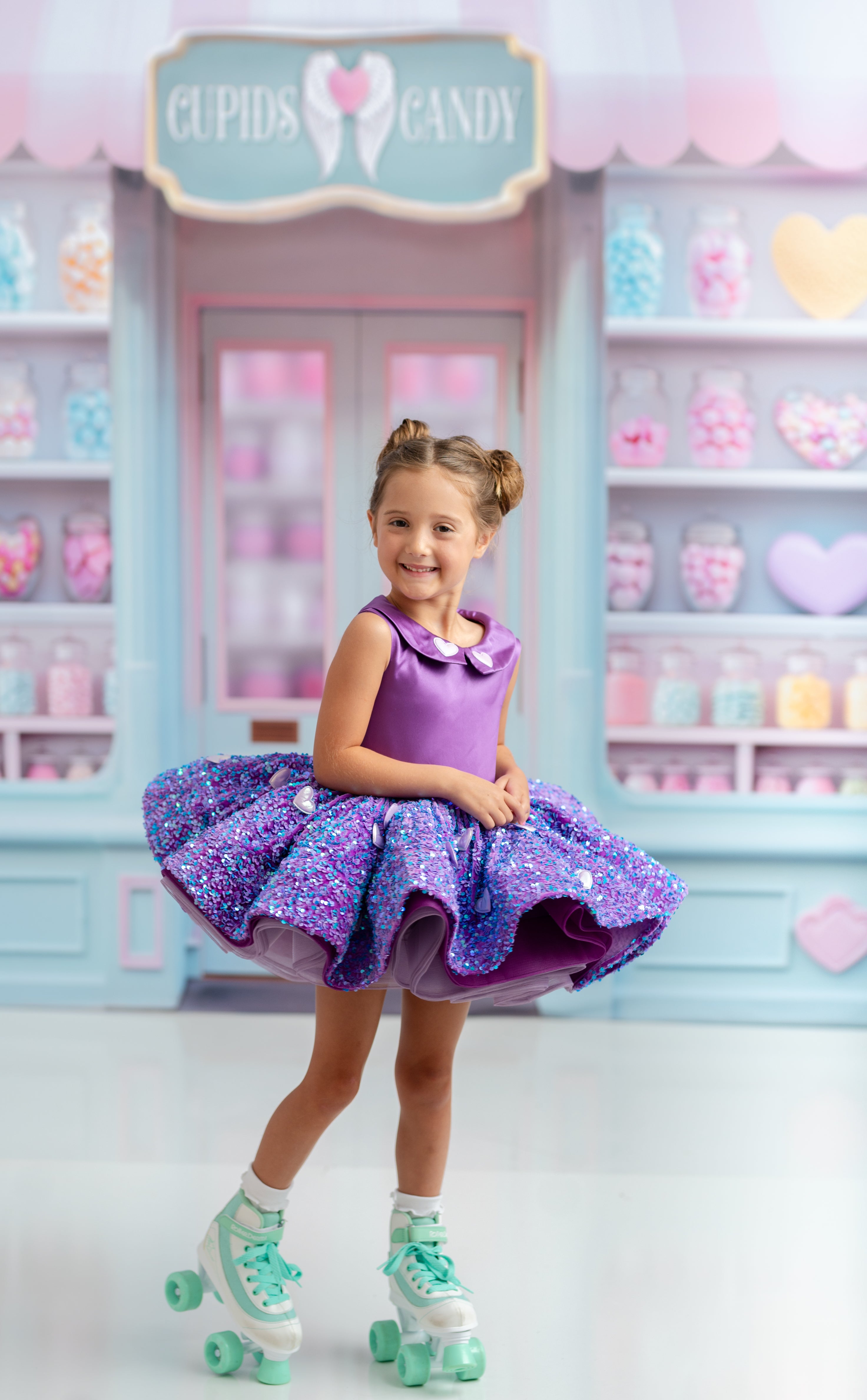 Toddler in purple sequin couture dress smiling in a studio photography session.
