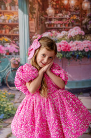 A statement couture dress with bold pink sequins and soft black tulle layers.
