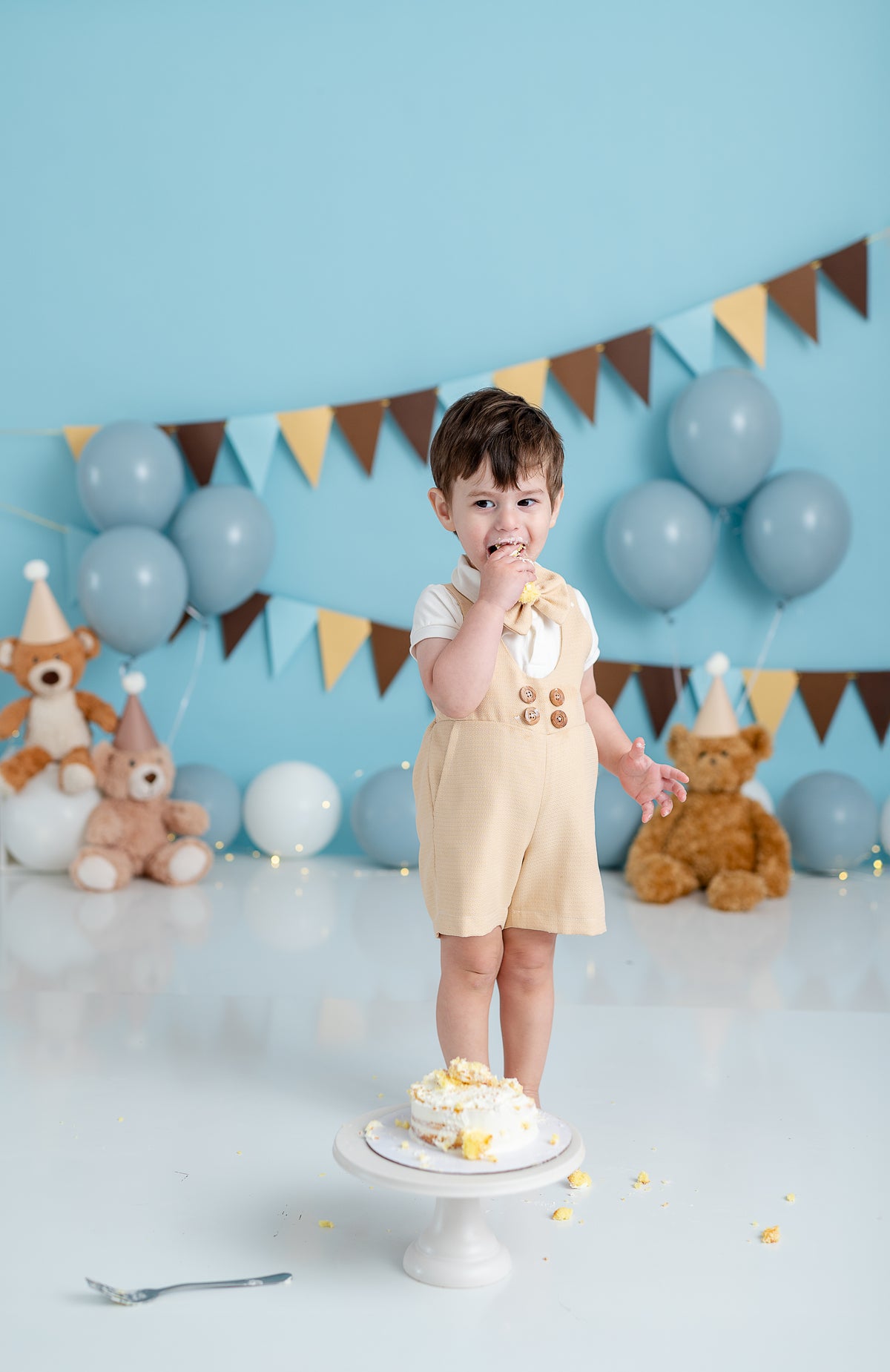​Charming suspender shorts with a natural finish, featuring pleated details and adjustable straps for a custom fit.​

