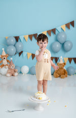 ​Charming suspender shorts with a natural finish, featuring pleated details and adjustable straps for a custom fit.​

