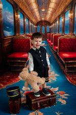 Child in formal attire with a teddy bear in a luxurious train car